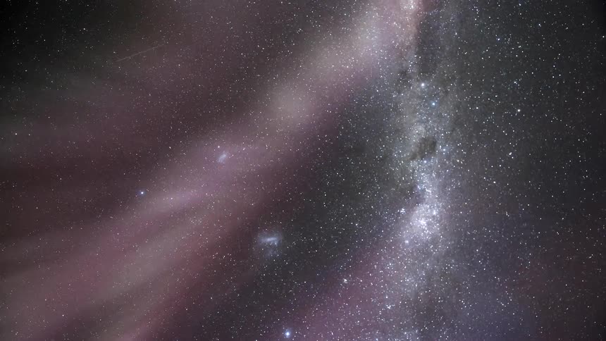 A beam of colored lights in the sky and it is full of stars