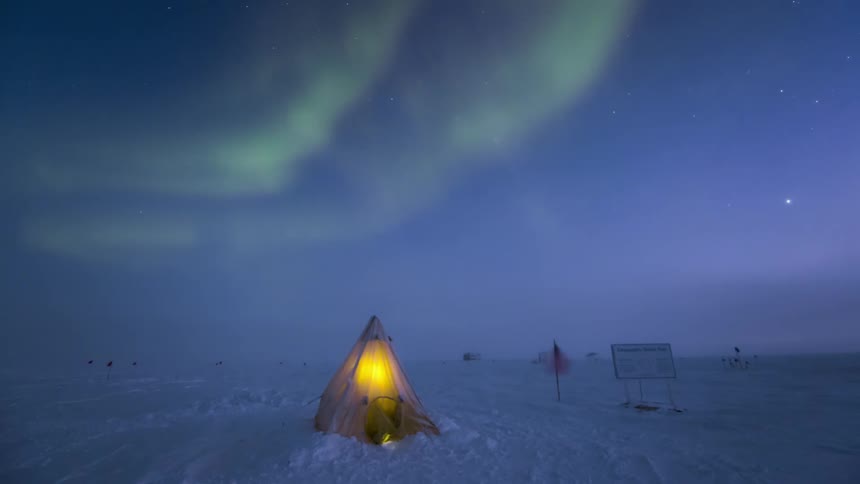 A person in a tent in the arctic during an atmospheric event