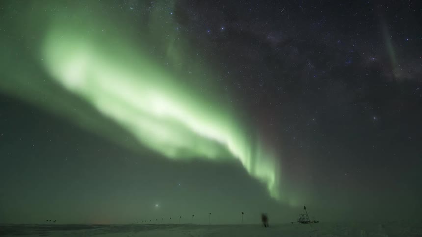 A person walking in antarctica at night illuminated by the Aurora Australis