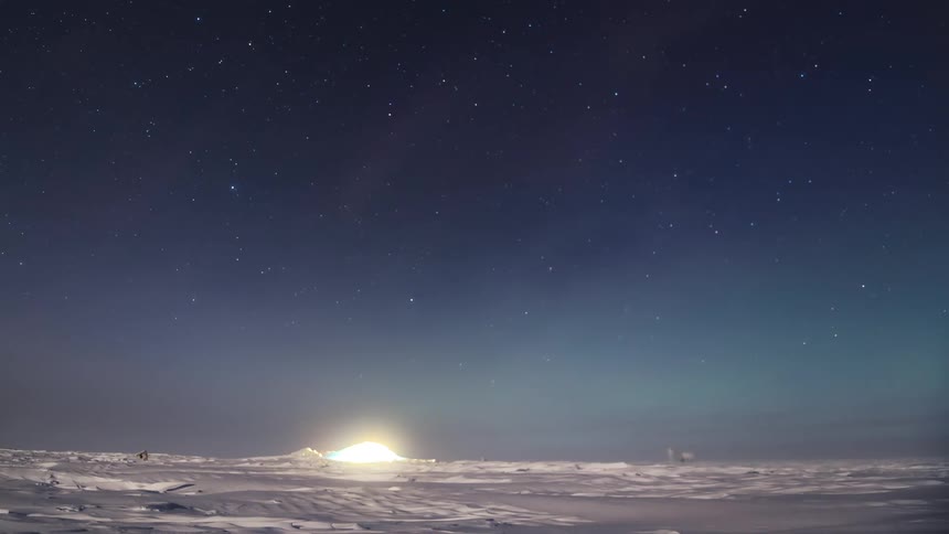 Landscape of a ground covered in snow at the north pole with the sky in Aurora Australis in timelapse