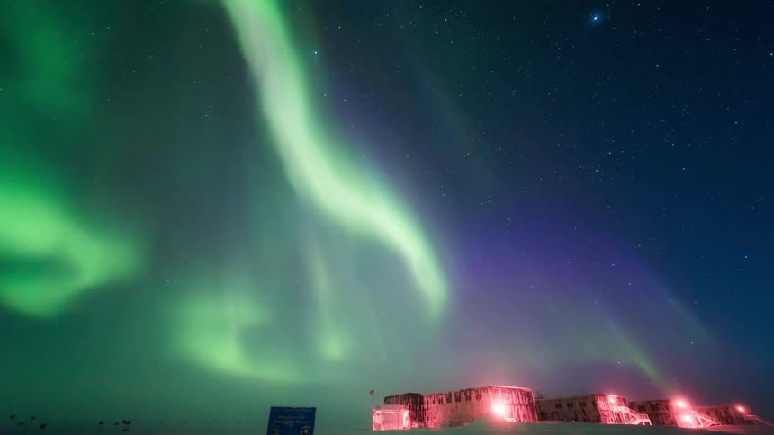 An aurora lights up the night sky over buildings