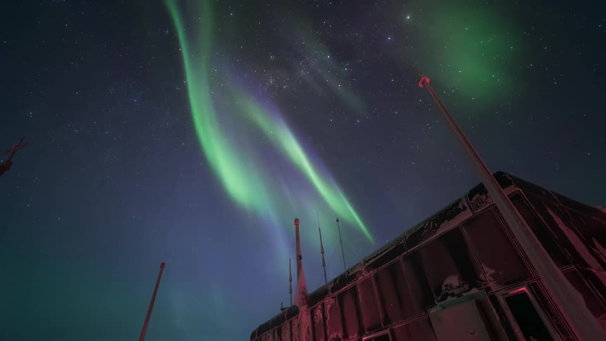 An aurora fills a sky above a building