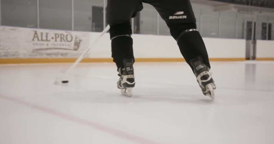 A hockey player is working a puck at the end of his stick
