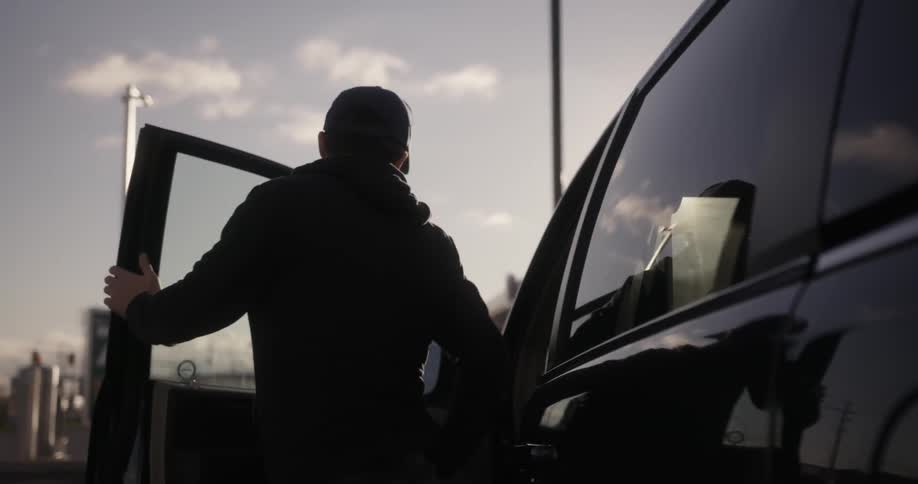 Man exiting his vehicle in a parking lot near sunset