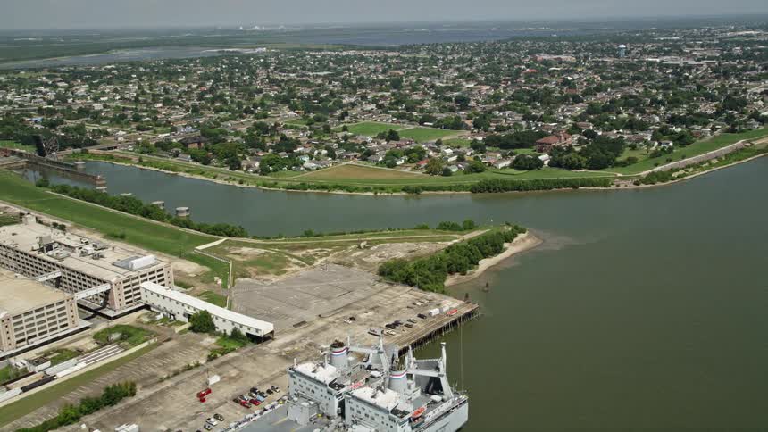Two cargo boats docked at an industrial pier near a suburban town