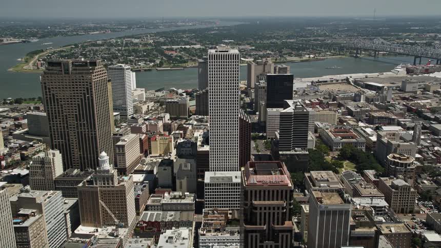 An aerial view of a city with a large river and a bridge in the background