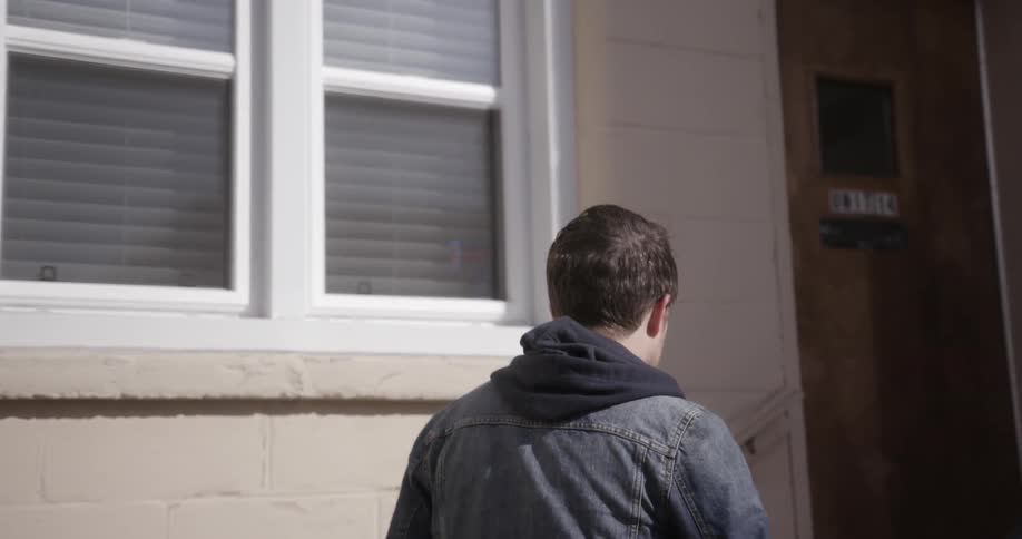 A man climbs a short flight of stairs and opens a door
