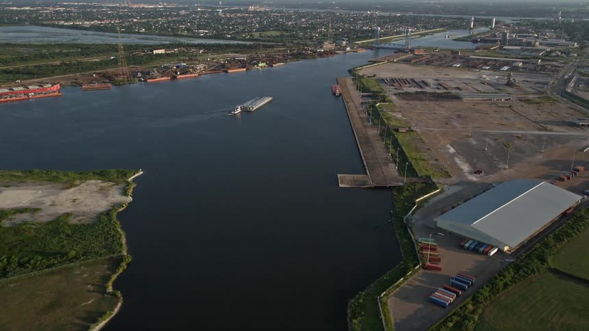 Aerial of a cargo ship sailing on a canal in a rural town