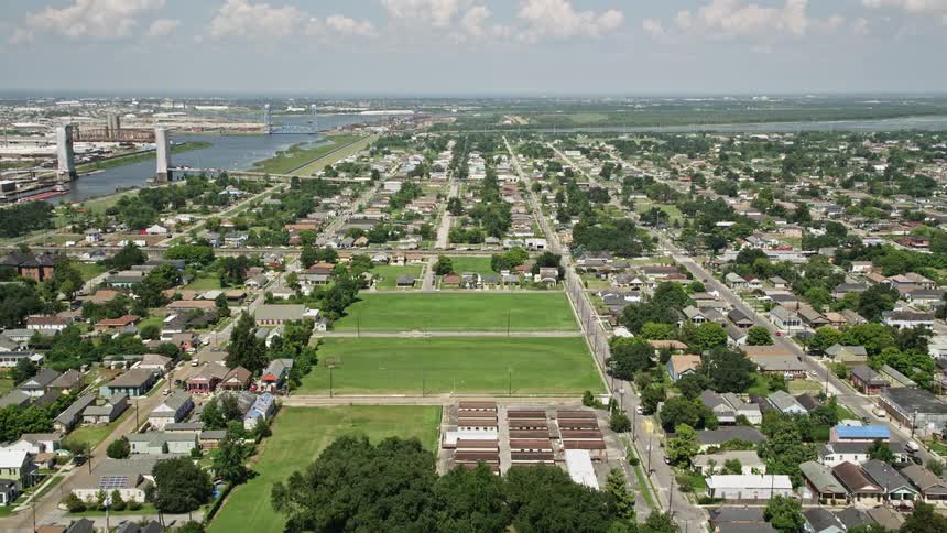 An aerial view of a city with a wide river and green spaces on a neighborhood