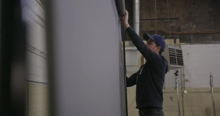 Man adjusting a projector screen