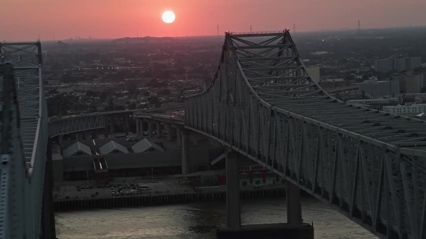 Aerial panorama of a bridge over the sea in the middle of a metropolis with the sunset on the horizon