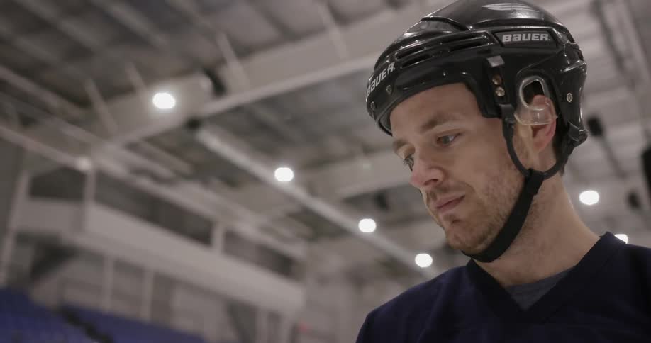 A man wearing a hockey helmet is thinking