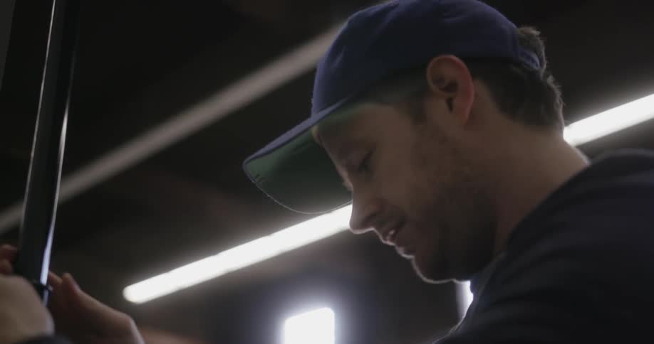 Man wearing a baseball cap adjusting something indoors