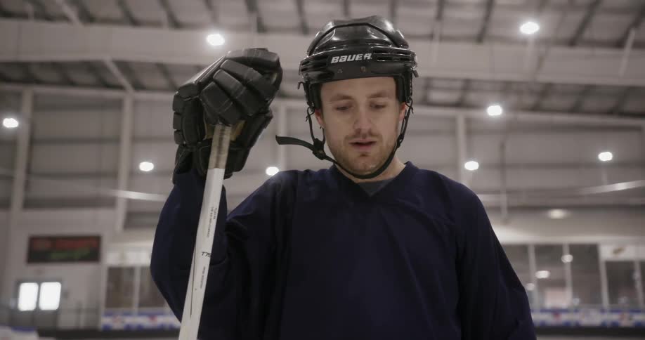 A hockey player stands on the ice gripping his stick
