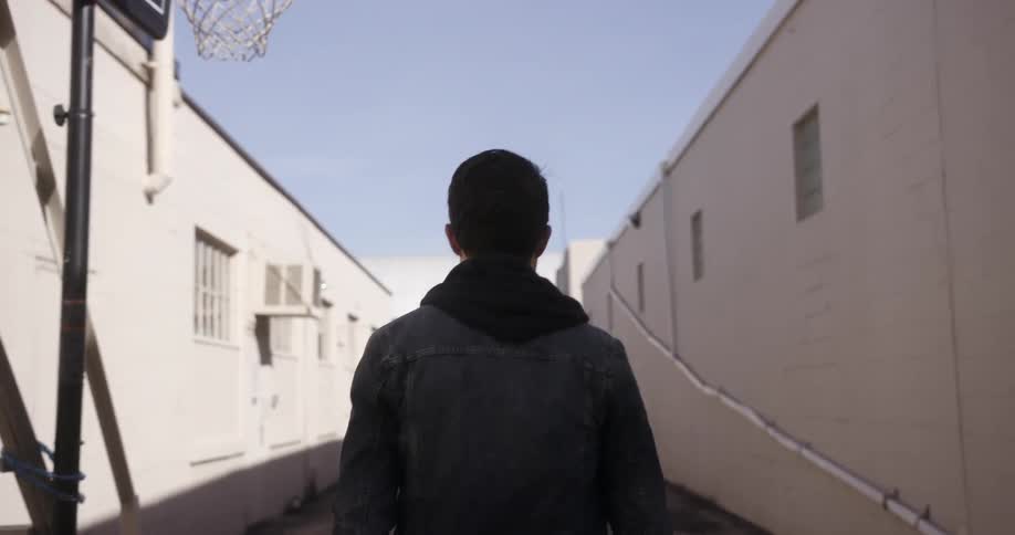 A man walks down an alley on a sunny day