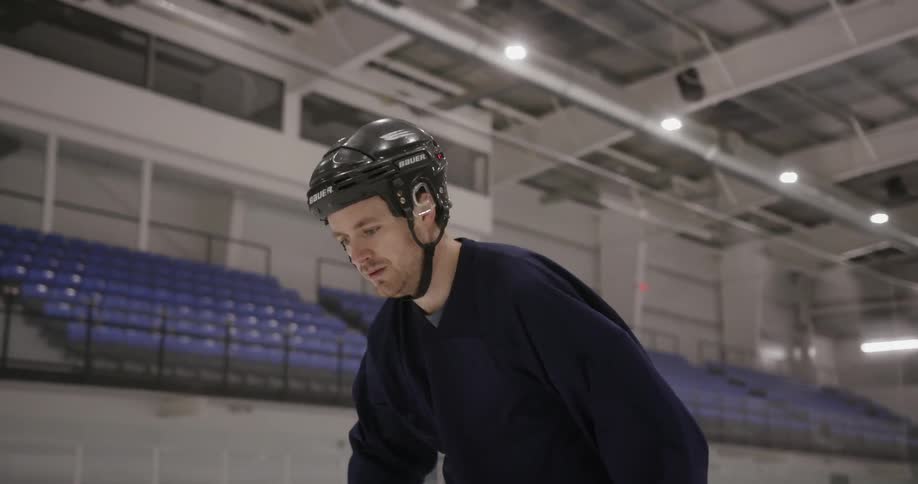 A man with a helmet skates on an ice rink