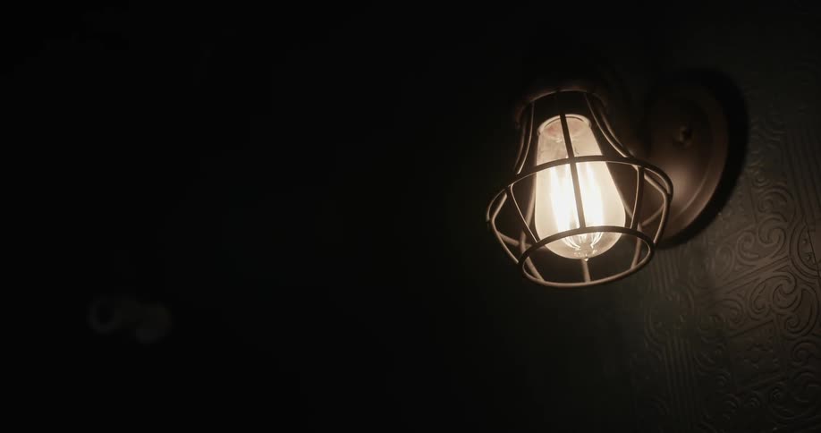 A light bulb in a steel sconce lights up