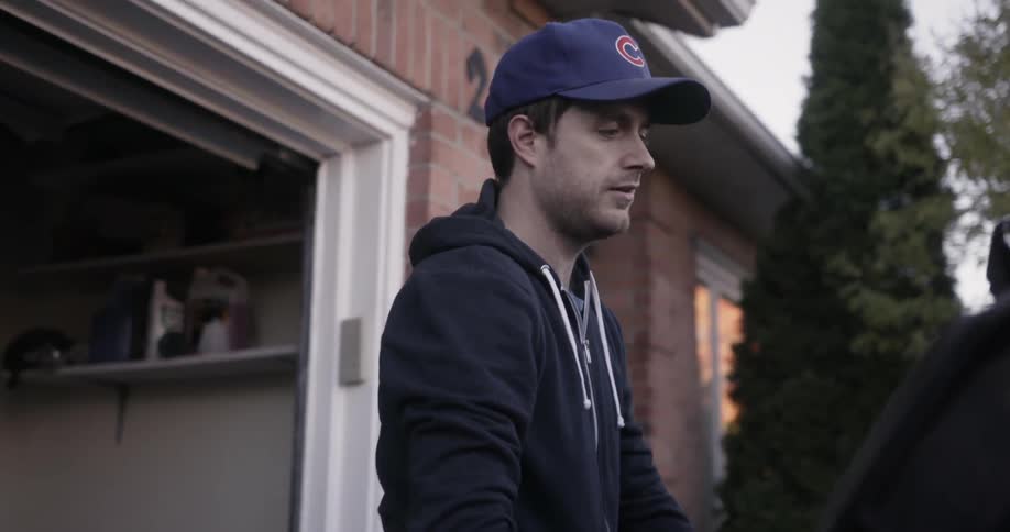 A man closing the trunk of his car outside a house