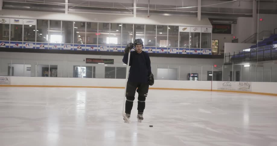 A hockey player stands on the ice in front of the puck