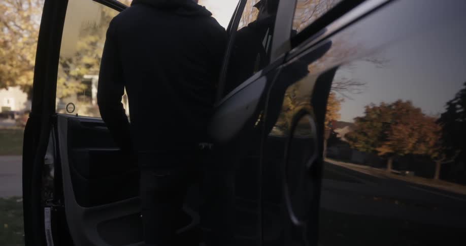 Man getting into his vehicle which is sitting in a driveway