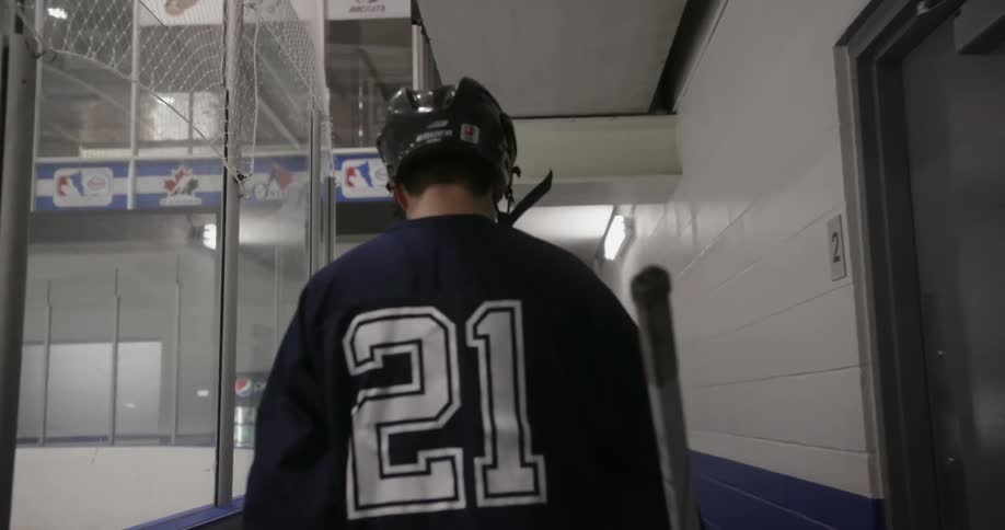 Man in hockey gear walking beside the ice