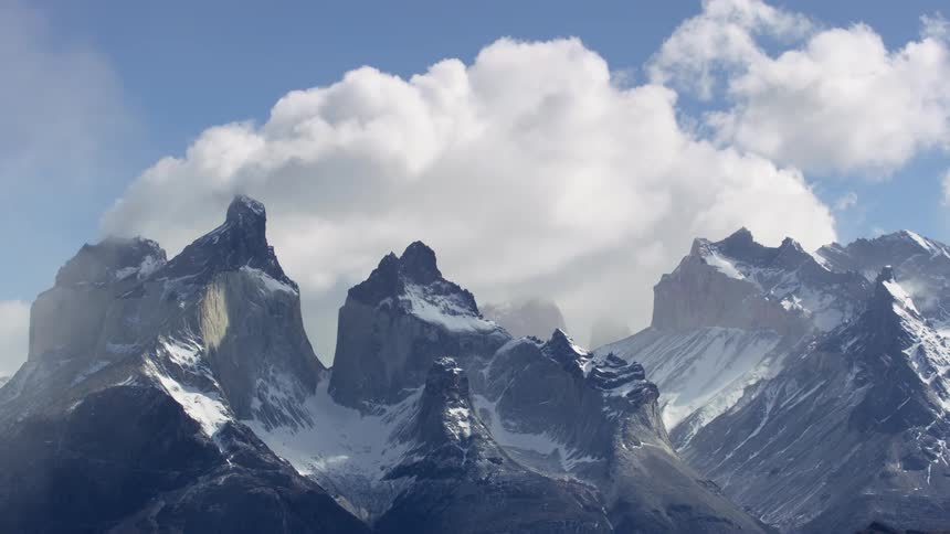 Clouds move over snow covered mountains