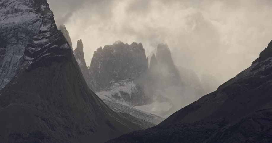 A mountain landscape with jagged peaks shrouded in mist and clouds