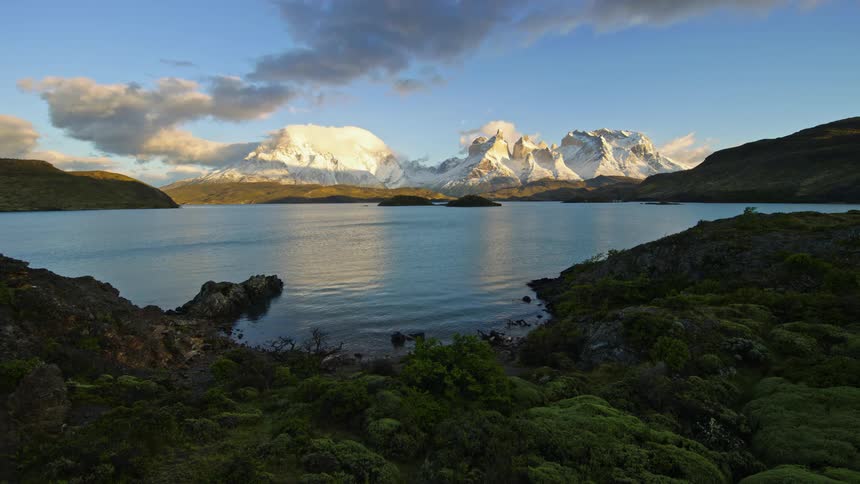 A serene landscape of a calm lake surrounded with majestic snowcapped mountains in the background
