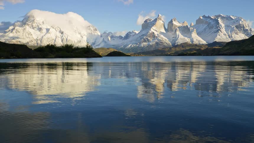 A landscape of a lake reflecting the snowcapped mountains in the background