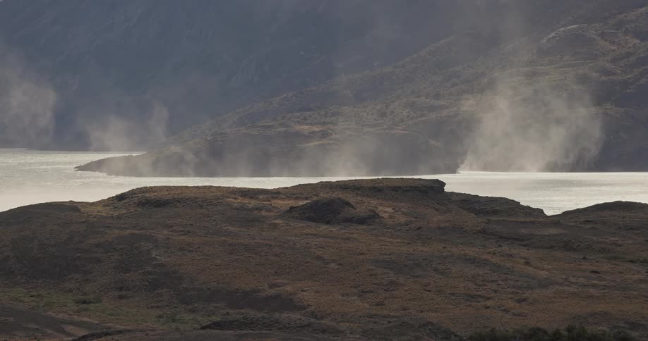 strong winds and eddies moving gusts of spray over a lake