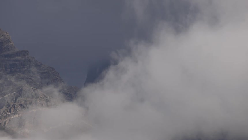 A mountainous landscape with clouds covering the peaks and a clear sky