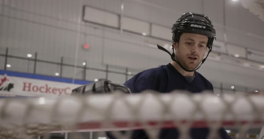 A man is walking around a goalie net
