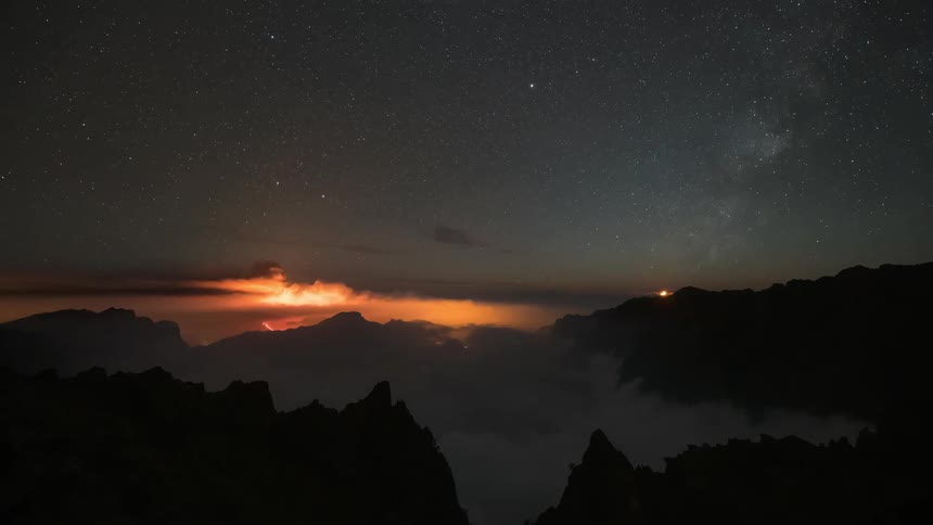 Clouds and fog move around mountains at dusk and into night