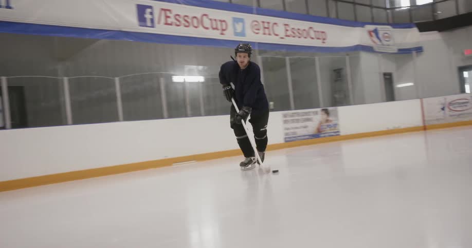 A man is practicing hockey on an ice rink