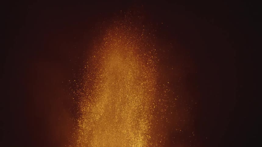 Close slow motion lava eruption spewing a fountain of orange flame and sparks at night