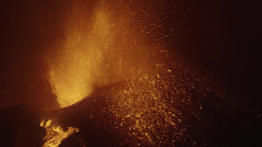 An erupting volcano with a river of lava on the mountain