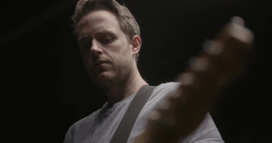 A man is playing an electric guitar indoors