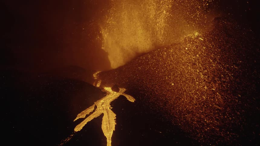 Lava spews out of a volcano and pools on a part of a mountain