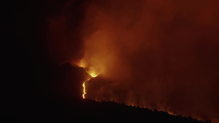 Aerial of an erupting volcanic mountain at night