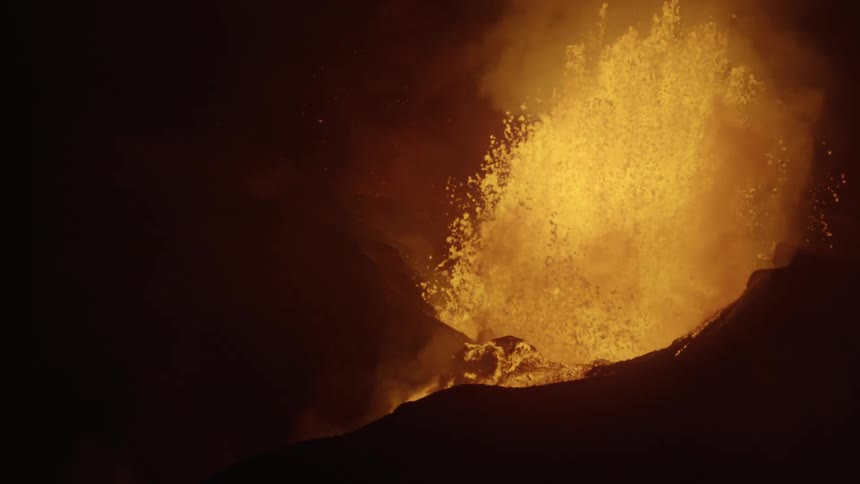 A volcano erupts at night