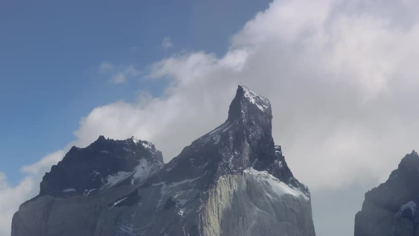 Passing clouds cast shadows onto snow dusted mountains