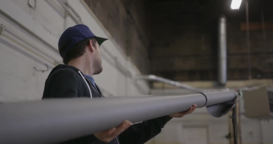 A man wearing a chicago cubs baseball caps affixes a grey reel to a frame