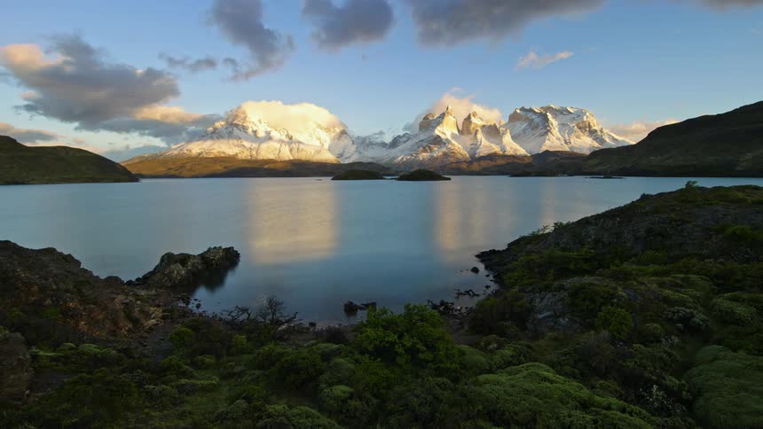 A time lapse of a lake with snow covered mountains in the distance