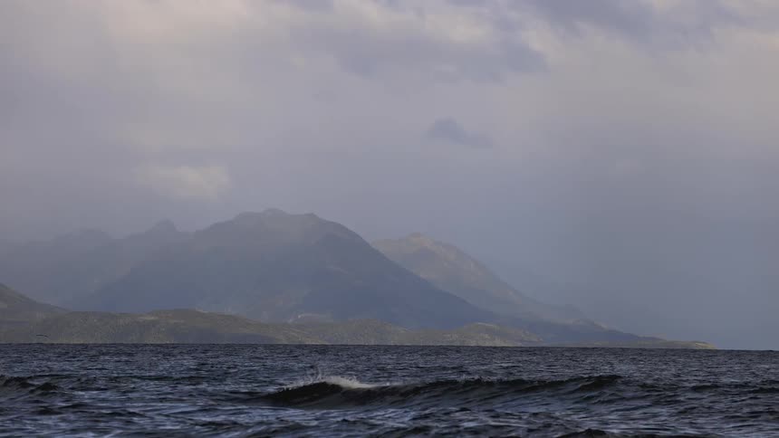 A beach surrounded by mountains during a cloudy day