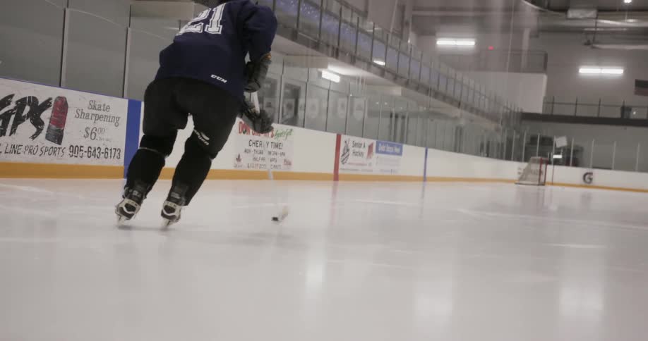 A man practicing hockey in an ice rink