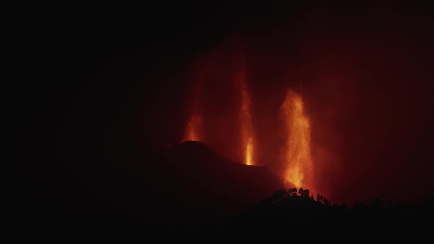 Three pillars of lava spew from an eruption into the night sky