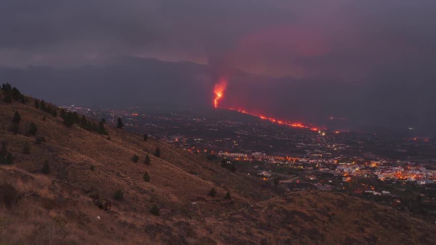 Traffic flows through city as volcano erupts and night falls