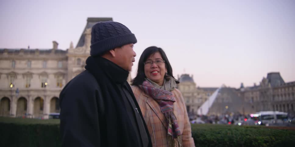 An asian couple walk through a city