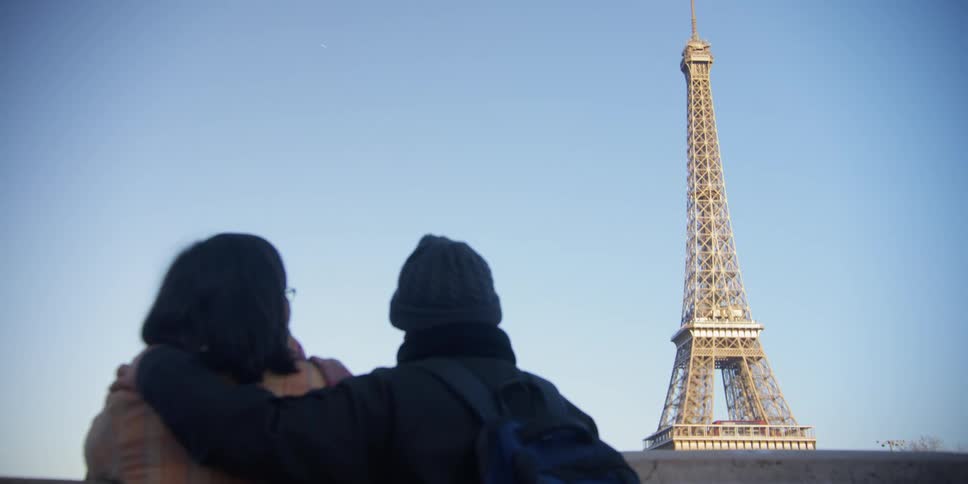 An asian couple look at the eiffel tower