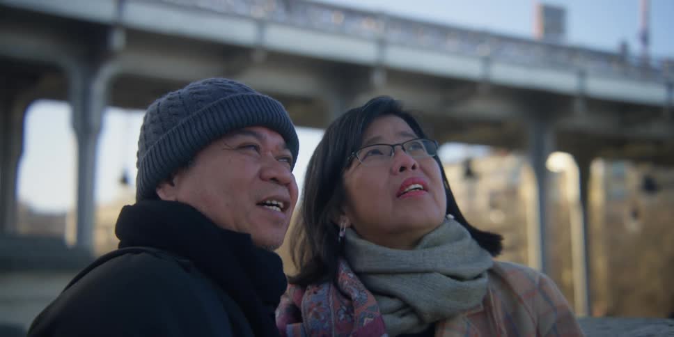 A man and women look at something in a city
